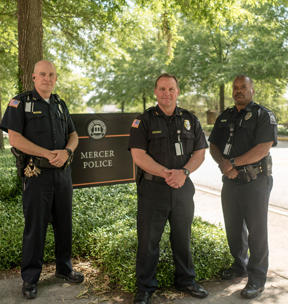 Three police offers standing in front of the Mercer Police sign